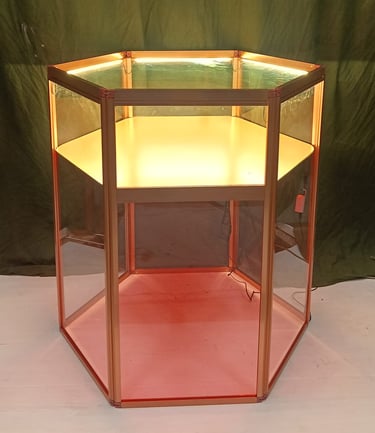 Hexagonal glass display case with built-in lighting and a bronze metal frame for retail or jewelry display.