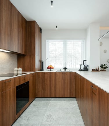 Nowoczesna kuchnia w kształcie U z drewnianymi frontami i jasnym blatem.