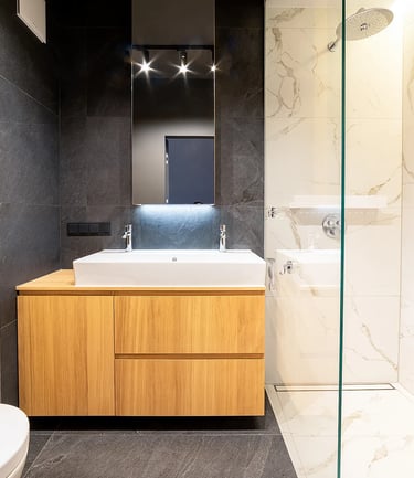 Nowoczesna łazienka z umywalką w drewnianej szafce, lustrem i przeszklonym prysznicem