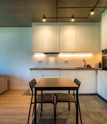 Nowoczesna kuchnia z białymi szafkami, czarną lodówką i stołem z czterema krzesłami