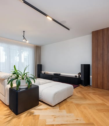 Nowoczesny salon z jasną sofą, drewnianą podłogą, zasłonami i niską szafką RTV.