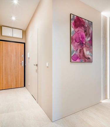 Jasny korytarz z drzwiami wejściowymi z drewna, lustrzaną szafą po lewej oraz obrazami na ścianach