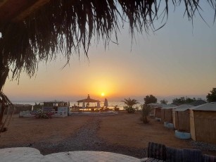 a sunset over a beach with a table and chairs