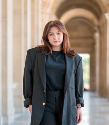 Portrait d’une modèle dans une galerie parisienne, habillée en noir, dans un décor élégant aux colonnes et arches en perspect