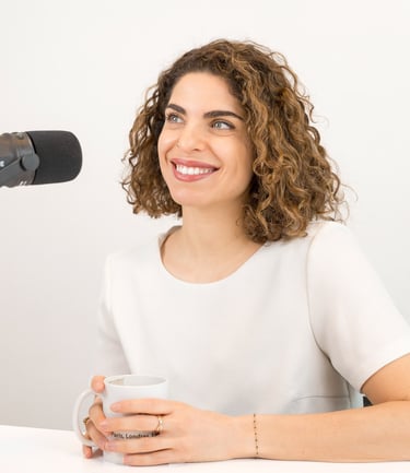 Portrait professionnel d’une femme souriante en studio, devant un micro, dans un cadre épuré et lumineux usage podcast