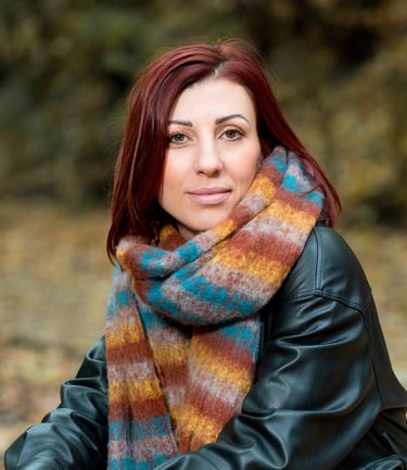 Portrait d’une comédienne en extérieur, vêtue d’une écharpe colorée et d’un blouson en cuir, avec un regard doux et confiant.