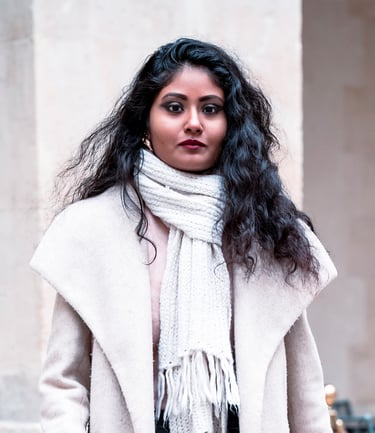 Portrait d’une modèle en manteau d’hiver clair et écharpe, posant avec assurance devant un mur beige.