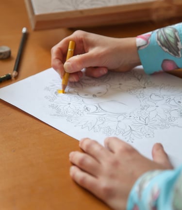 Hands making a koala illustration with colored pencils