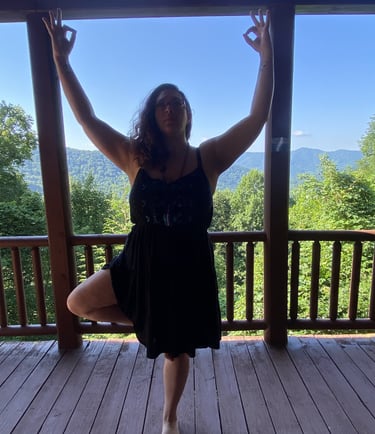 Rachel on balcony doing yoga with mountain range and tall trees and background