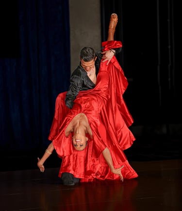 A man lifts a woman wearing a vibrant red satin skirt on the dance floor