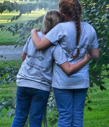 Two daughters hugging wearing Jack’s Lovksmith T-shirts, representing local locksmith of Nebo family values