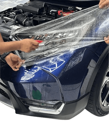 : Technician applying paint protection film to car headlight at One 7 Garage