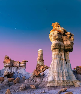 Ancient rock hoodoos in the New Mexico desert under a purple and blue twilight sky.
