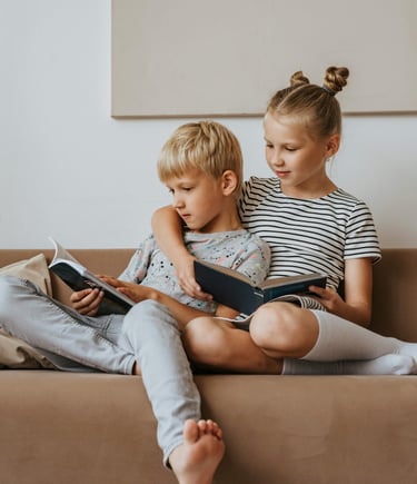 two children on a couch with books
