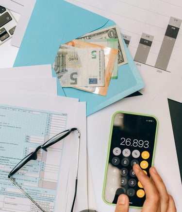 a phone, glasses, paper and a blue envelope with money on a table