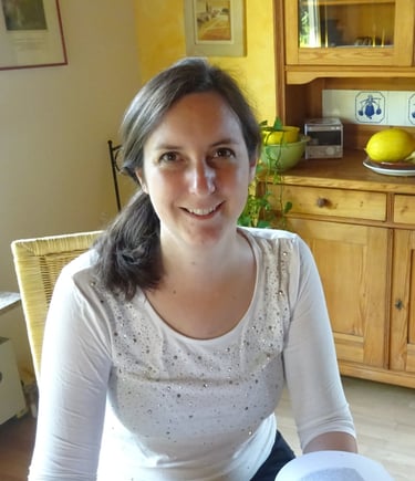 a friendly smiling woman sitting at a table with a book