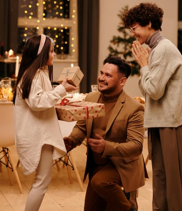 a man and woman and child holding a present in a room