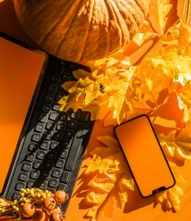 a cell phone and a keyboard on a table with orange leaves