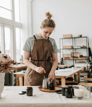 a woman in a brown apron is crafting behind a table