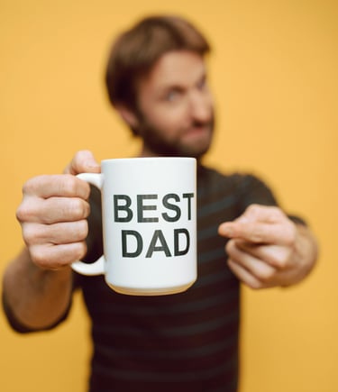 man holding white cup with best dad written on it
