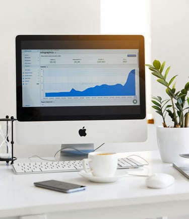 a computer monitor screen showing a graph, a cup of coffee and a plant on a table