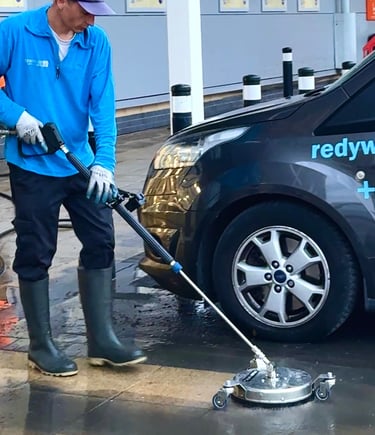 a man in a blue shirt is cleaning a patio using a pressure washing tool