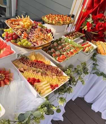 Mesa de catering gourmet con tablas de embutidos, tablas de quesos, brochetas caprese y aperitivos 