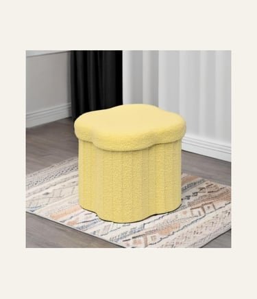 Yellow scalloped storage ottoman in textured sherpa fabric on a patterned rug in a modern living room.