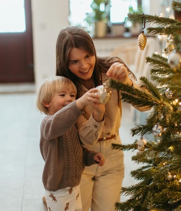 a woman and a child are standing in front of a christmas tree