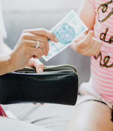 a woman is holding a purse and gives money to daughter