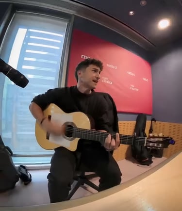 A male musician playing an spanish guitar during a live performance at the RNE radio studio.