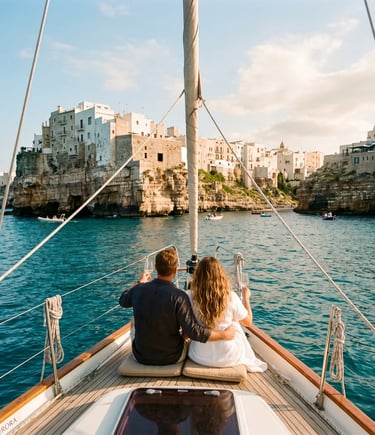 Couple sitting on sailboat bow facing Polignano a Mare white cliffs, turquoise Adriatic Sea