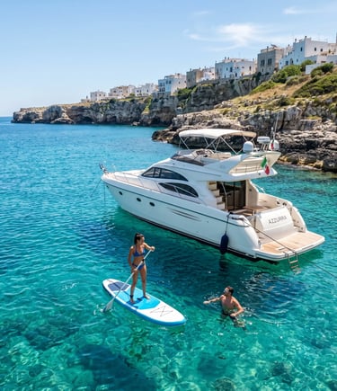 Luxury yacht anchored near Polignano a Mare cliffs with woman on SUP board and swimmer in sea
