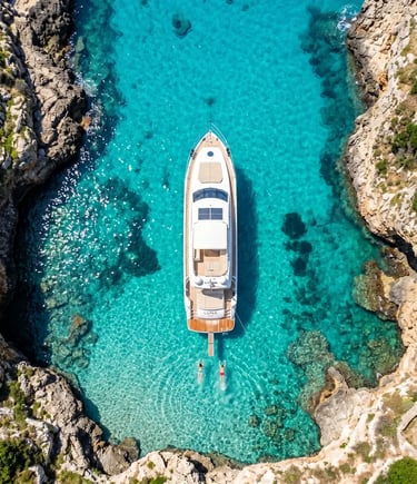 Aerial view of private luxury boat anchored in turquoise cove with swimmers, Puglia Italy