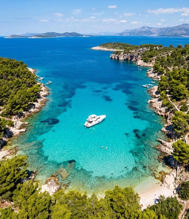Drone shot of crystal clear turquoise bay with white private boat anchored inside