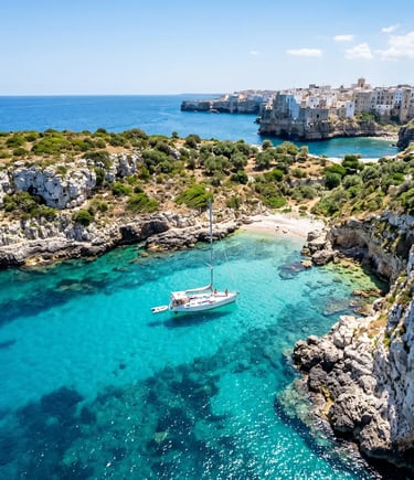 Aerial view of white sailboat anchored in turquoise cove near Polignano a Mare