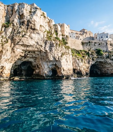 View from the sea of dramatic white limestone cliffs with cave openings and whitewashed buildings above