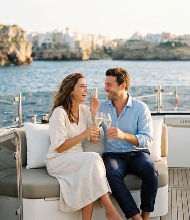 Couple toasting prosecco on luxury yacht Libertá with Polignano a Mare cliffs in background