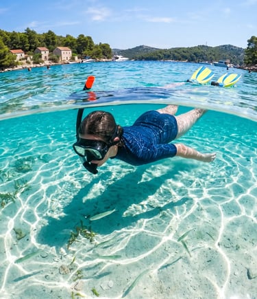 Underwater split shot of snorkeler gliding over sandy bottom in turquoise Croatian bay