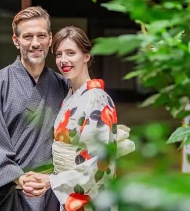 Happy couple in matching kimono smiling together in lush green Japanese garden Kyoto