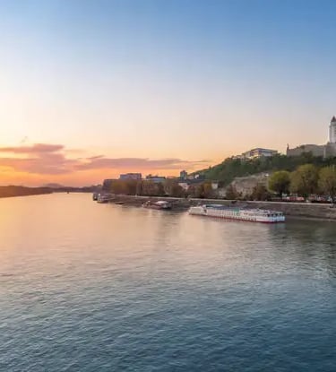 Panoramic sunset view of Bratislava Castle above the Danube River with cruise ship
