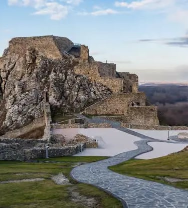 Stone ruins of Devín Castle on a rocky hilltop with winding path and winter landscape
