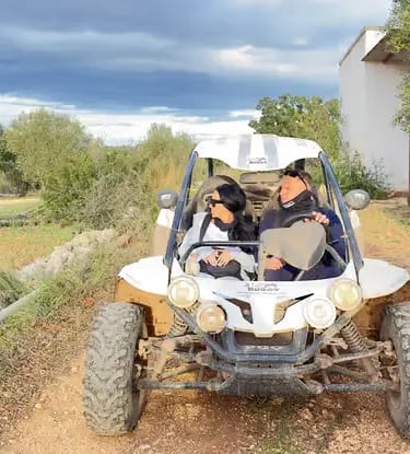 Couple riding white off-road buggy on rural dirt track in Apulia, southern Italy