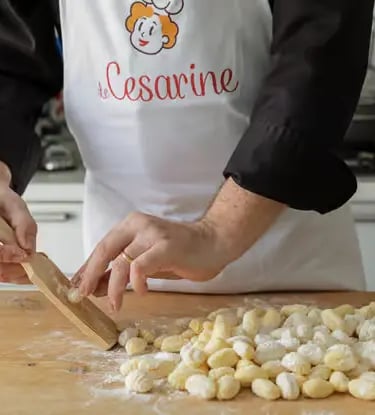 Cesarine chef hands rolling fresh gnocchi on wooden board during Lecce pasta cooking class