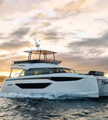 Prestige M48 power catamaran at golden hour with dramatic sunset sky on water