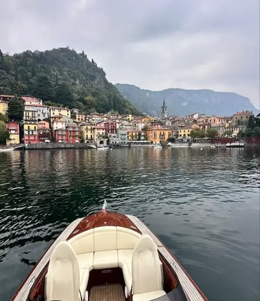 Wooden boat bow view approaching colorful Varenna village on Lake Como Italy