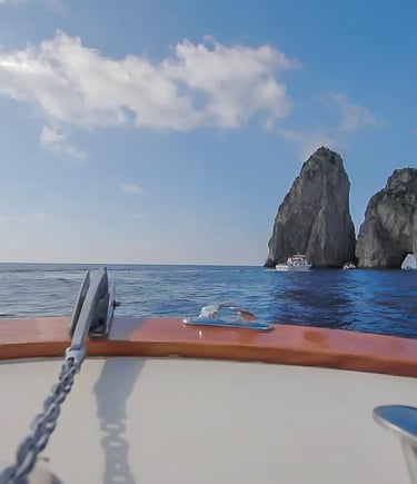 View from private boat tour approaching the Faraglioni rock arch in Capri Italy