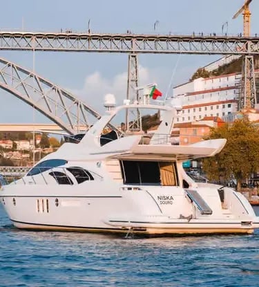 White luxury yacht sailing under Ponte Luís I bridge on the Douro River in Porto