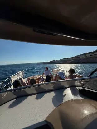 Group relaxing on private charter boat deck cruising Adriatic coast near Castro Puglia