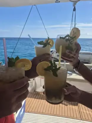 Friends toasting fresh cocktails on a catamaran with open Balearic Sea behind
